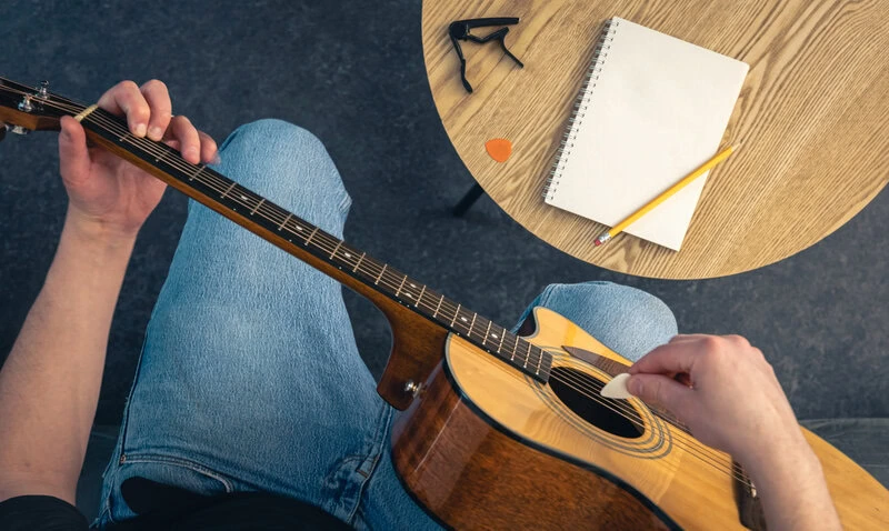 man with acoustic guitar notepad table top view